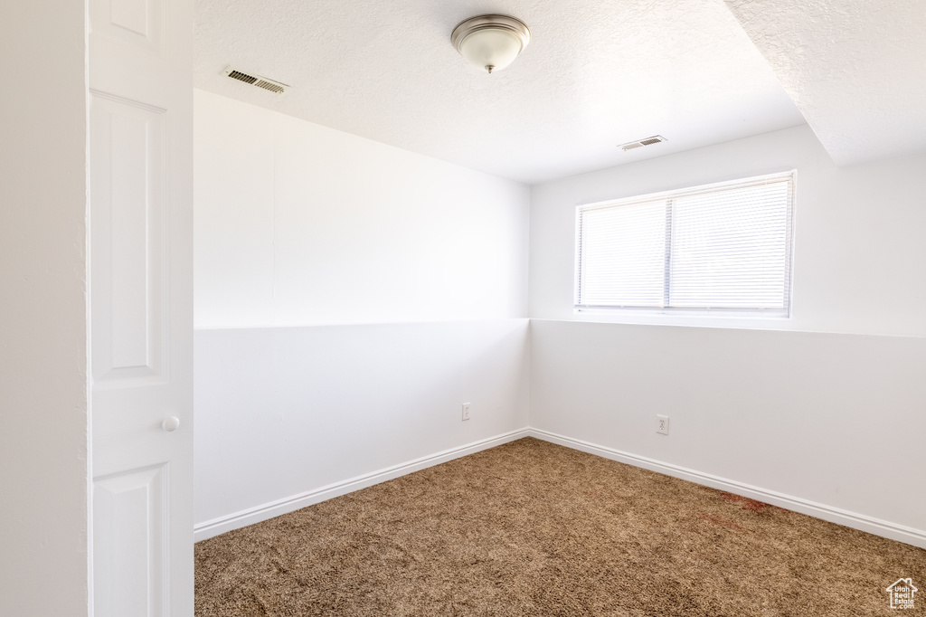 Unfurnished room featuring a textured ceiling and carpet flooring