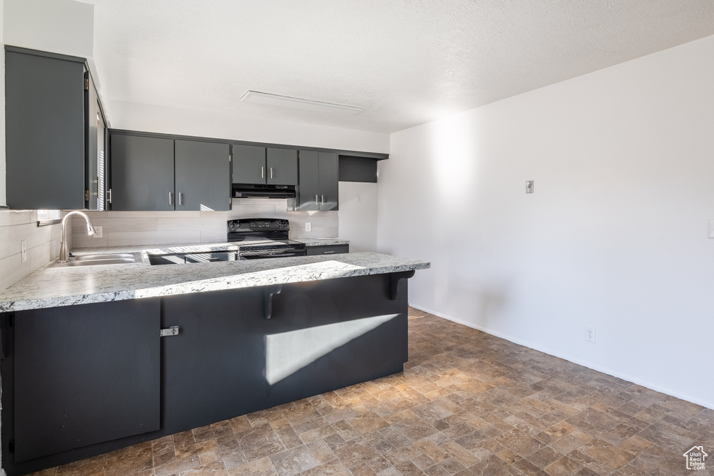 Kitchen featuring backsplash, kitchen peninsula, sink, gray cabinets, and black range with electric cooktop