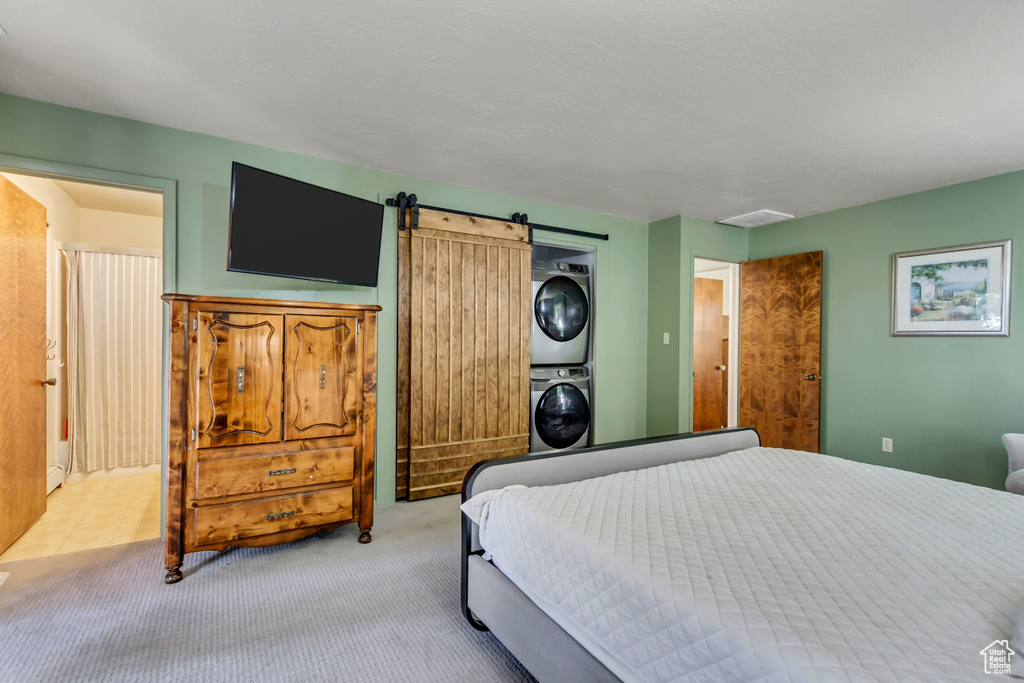 Carpeted bedroom featuring stacked washer / dryer and a barn door