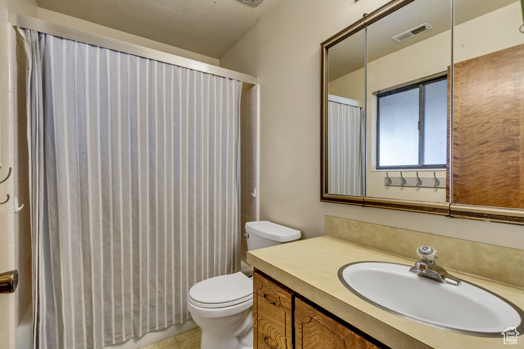 Bathroom featuring vanity, toilet, walk in shower, and tile patterned floors