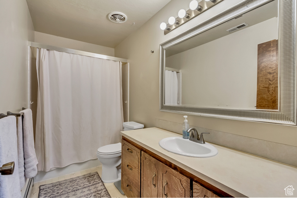 Bathroom featuring curtained shower, tile patterned floors, toilet, and vanity