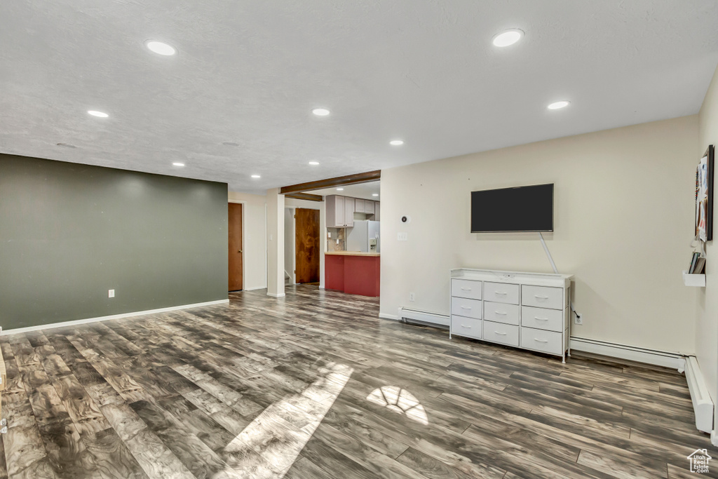 Unfurnished living room with a baseboard heating unit and hardwood / wood-style flooring