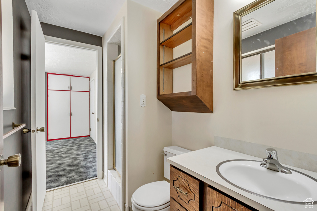 Bathroom with a shower with door, vanity, and toilet