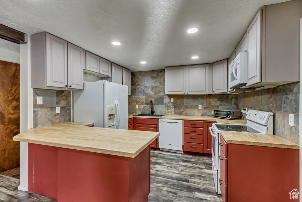 Kitchen with backsplash, wood counters, white appliances, dark hardwood / wood-style flooring, and sink