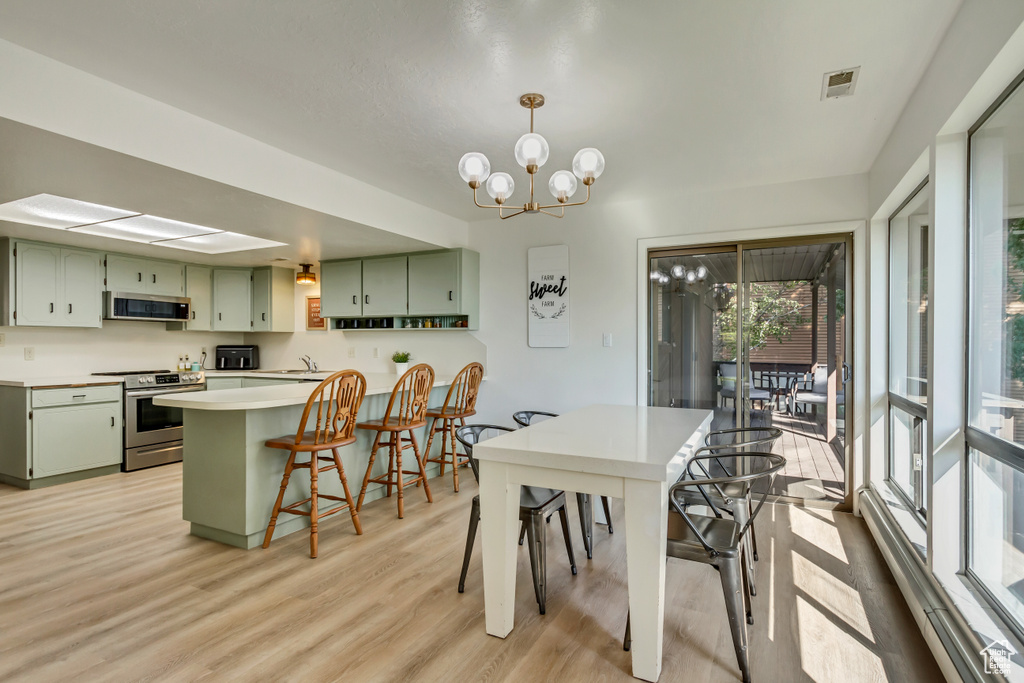 Dining space with light hardwood / wood-style flooring and an inviting chandelier