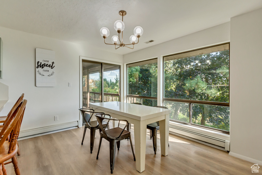 Dining space with a baseboard heating unit, plenty of natural light, and light hardwood / wood-style floors