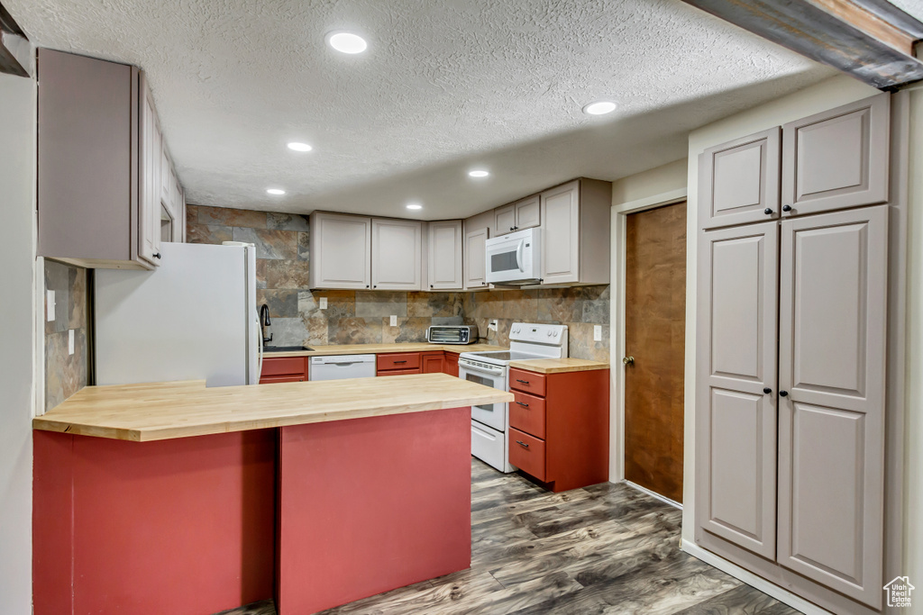 Kitchen with white appliances, dark hardwood / wood-style flooring, wood counters, and a textured ceiling