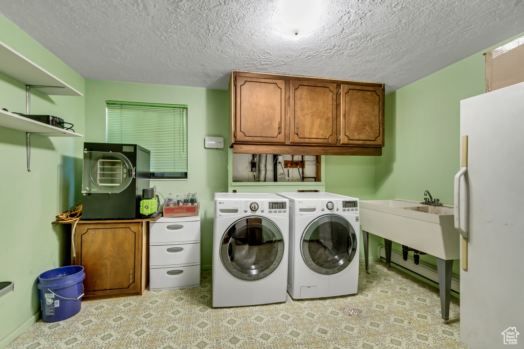 Laundry area featuring washer and dryer, cabinets, and a textured ceiling