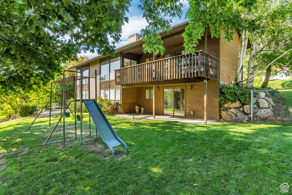 Back of house featuring a yard and a playground