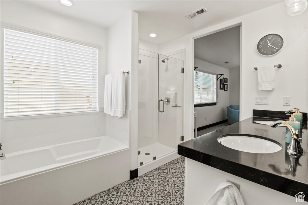 Bathroom featuring shower with separate bathtub and vanity