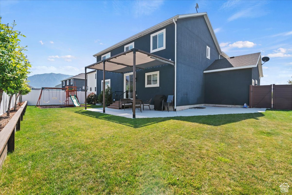 Rear view of house featuring a mountain view, a playground, a patio area, and a lawn