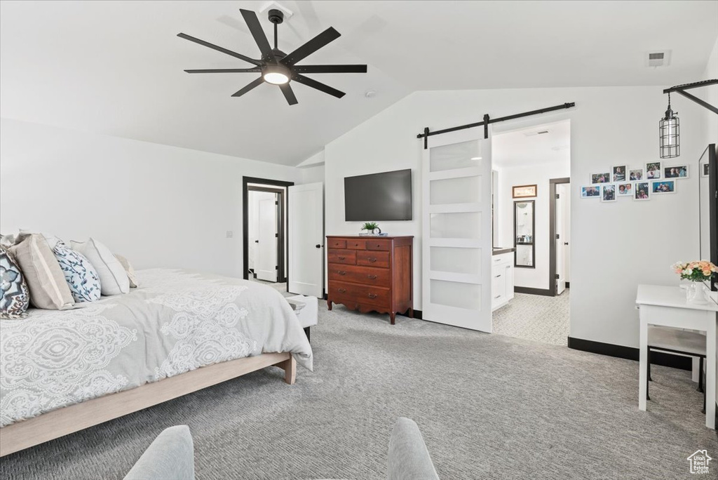 Carpeted bedroom featuring lofted ceiling, ceiling fan, and a barn door