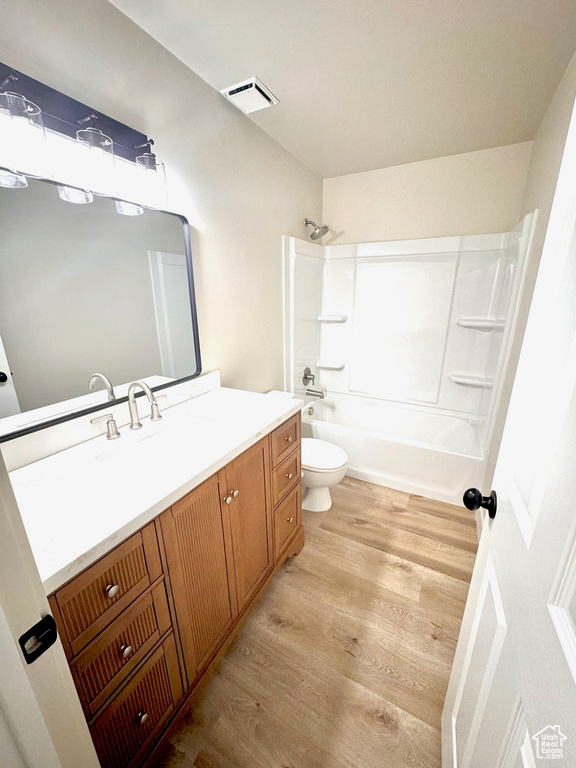 Full bathroom with vanity, toilet, hardwood / wood-style flooring, and shower / tub combination