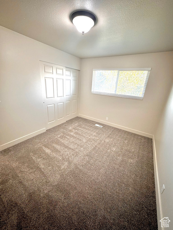 Carpeted spare room with a textured ceiling