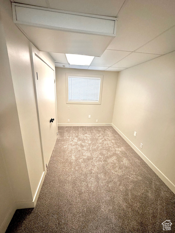 Basement with a paneled ceiling and light colored carpet