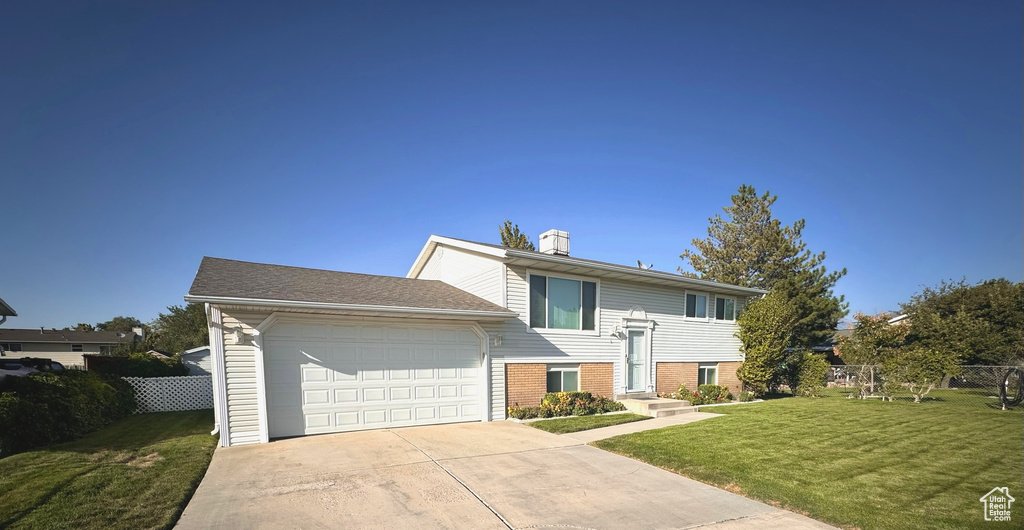 Bi-level home with a front yard and a garage