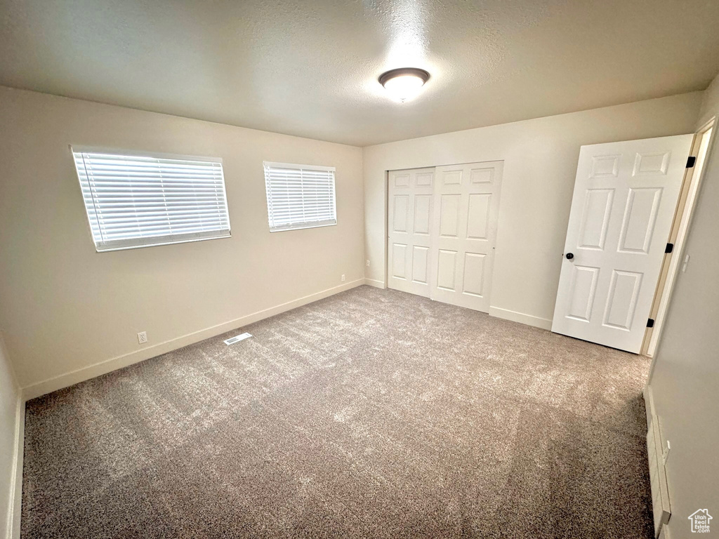 Unfurnished bedroom featuring a closet, carpet flooring, and a textured ceiling