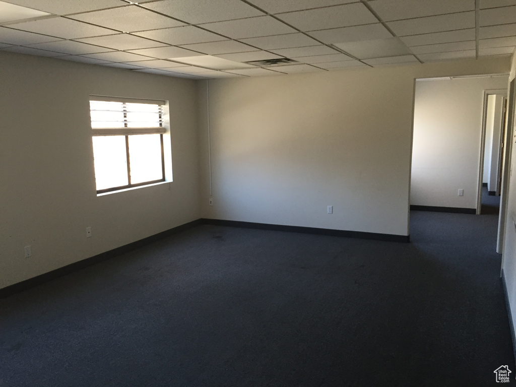 Spare room with a paneled ceiling and dark carpet