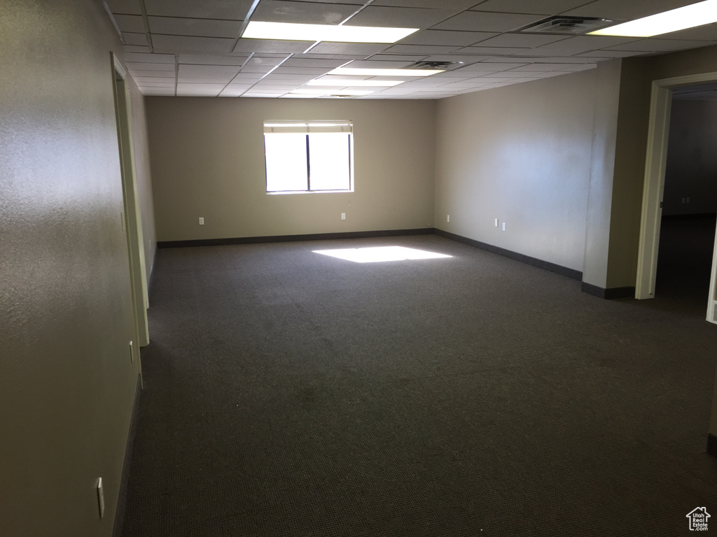 Spare room featuring a paneled ceiling and dark carpet