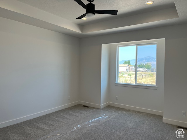 Carpeted empty room with a tray ceiling, a textured ceiling, and ceiling fan