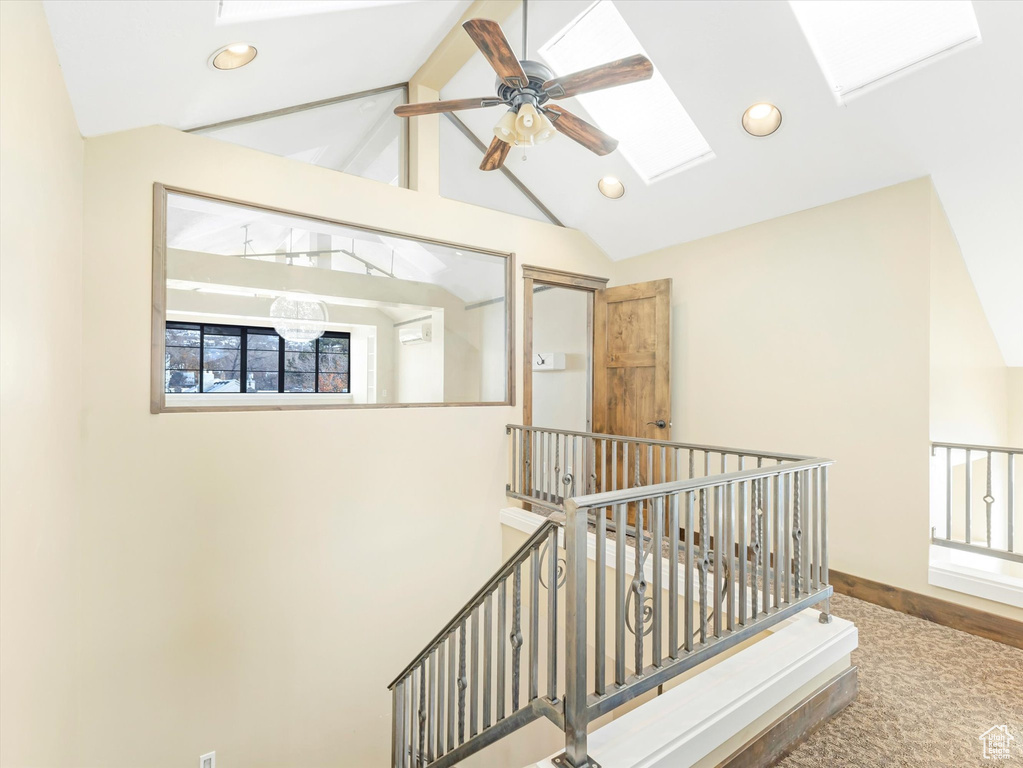 Stairs featuring carpet, a skylight, ceiling fan, high vaulted ceiling, and beamed ceiling