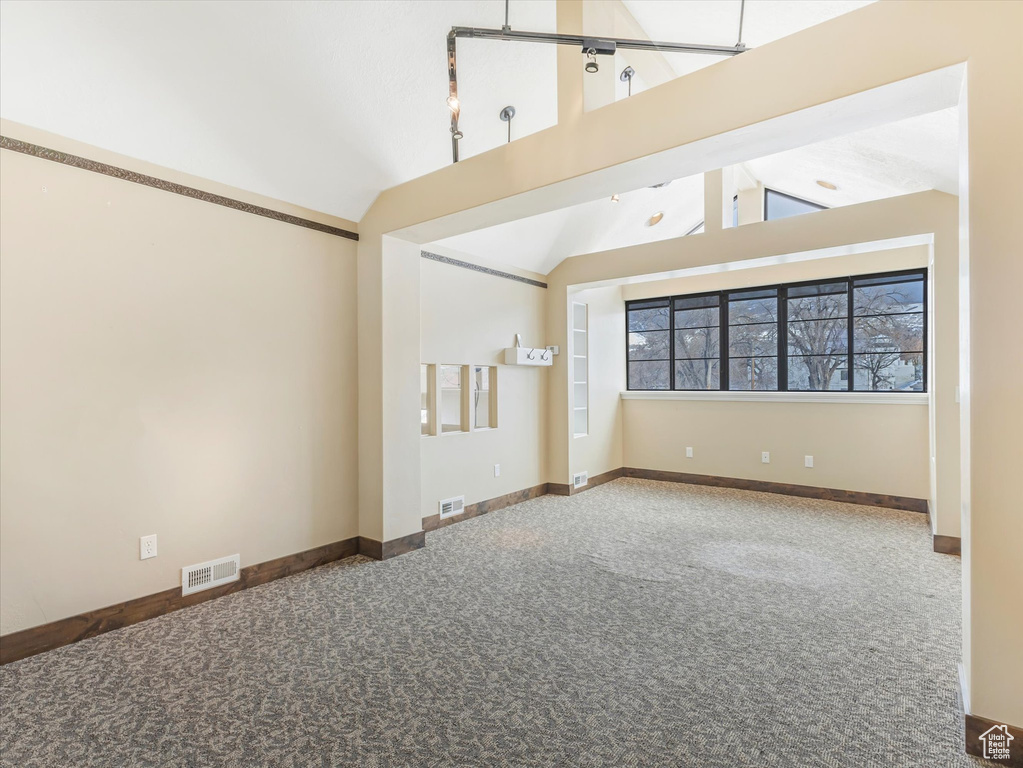 Unfurnished room featuring carpet floors and high vaulted ceiling