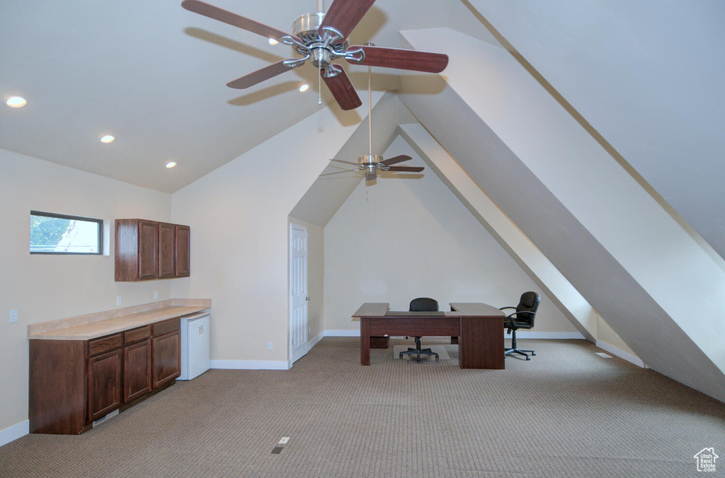 Additional living space featuring lofted ceiling, built in desk, ceiling fan, and light colored carpet