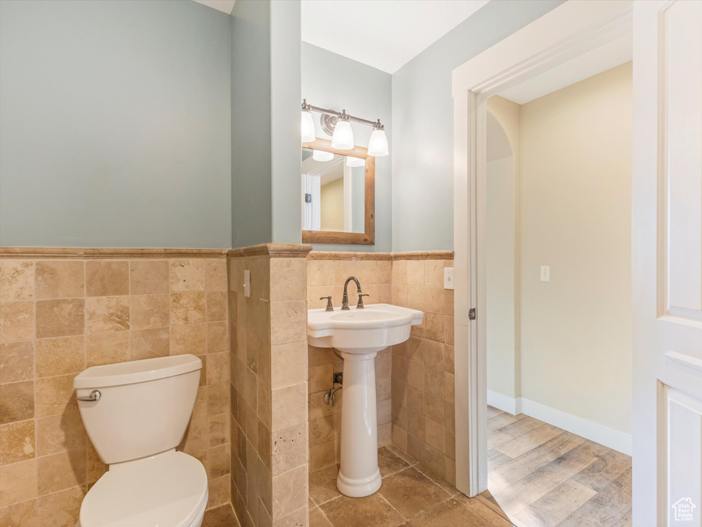 Bathroom featuring wood-type flooring, tile walls, and toilet