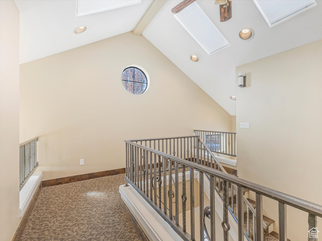 Corridor featuring carpet, beam ceiling, and high vaulted ceiling