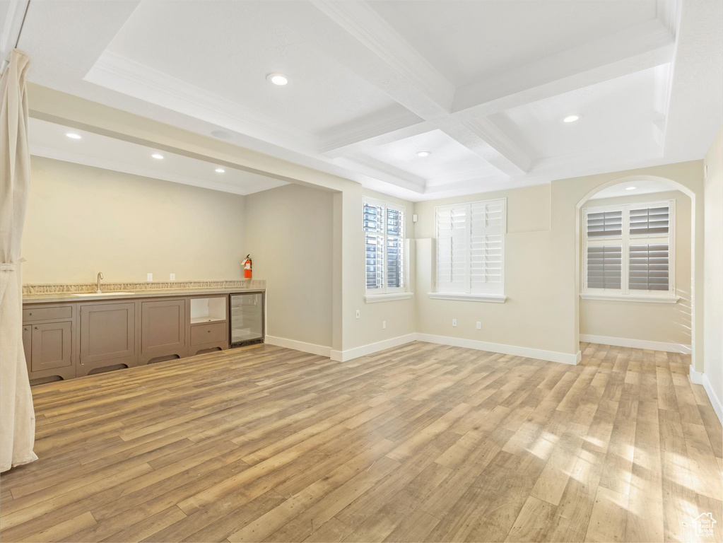 Interior space featuring sink, beverage cooler, coffered ceiling, beamed ceiling, and light hardwood / wood-style floors