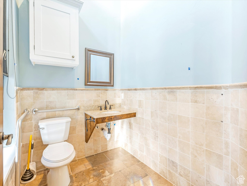 Bathroom featuring tile walls and toilet