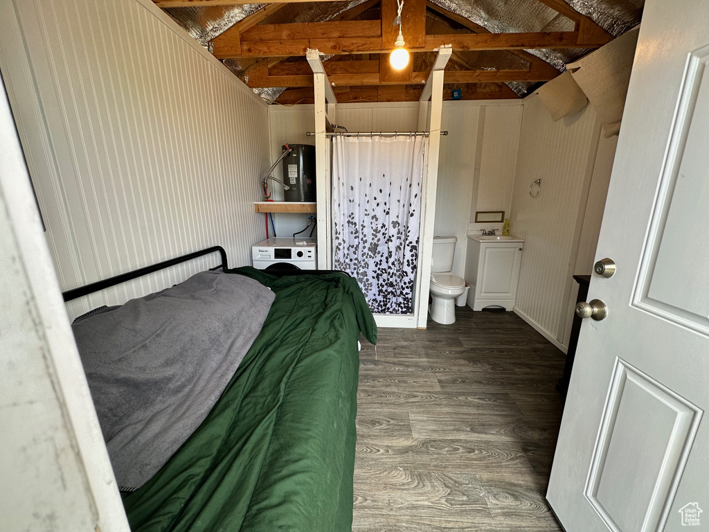 Bedroom with dark wood-type flooring, connected bathroom, sink, and lofted ceiling with beams