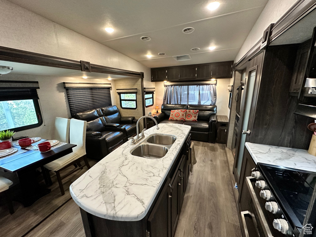 Kitchen featuring high quality range, wood-type flooring, a center island with sink, and sink