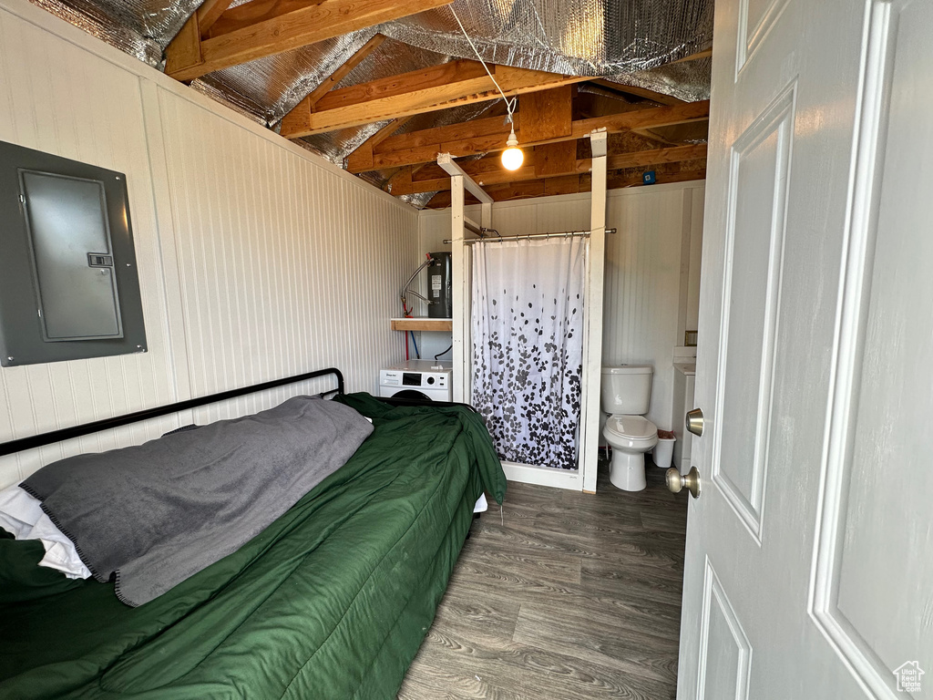 Bedroom with connected bathroom, wood walls, electric panel, dark hardwood / wood-style floors, and lofted ceiling with beams