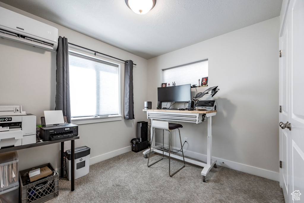 Office area featuring a wall mounted AC and light colored carpet