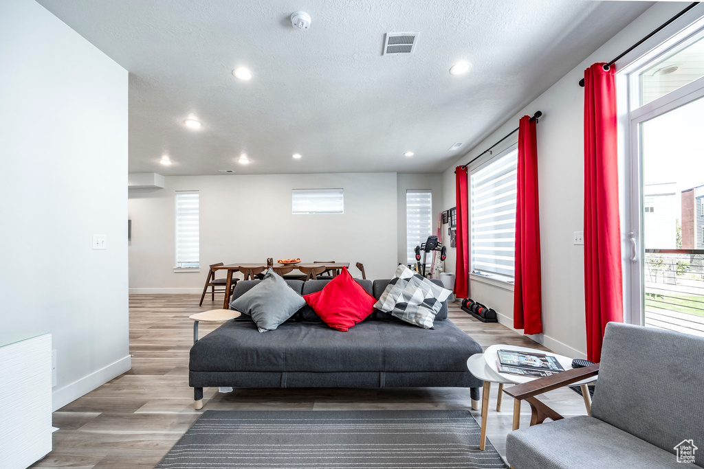Living room with baseboards, light wood finished floors, and recessed lighting
