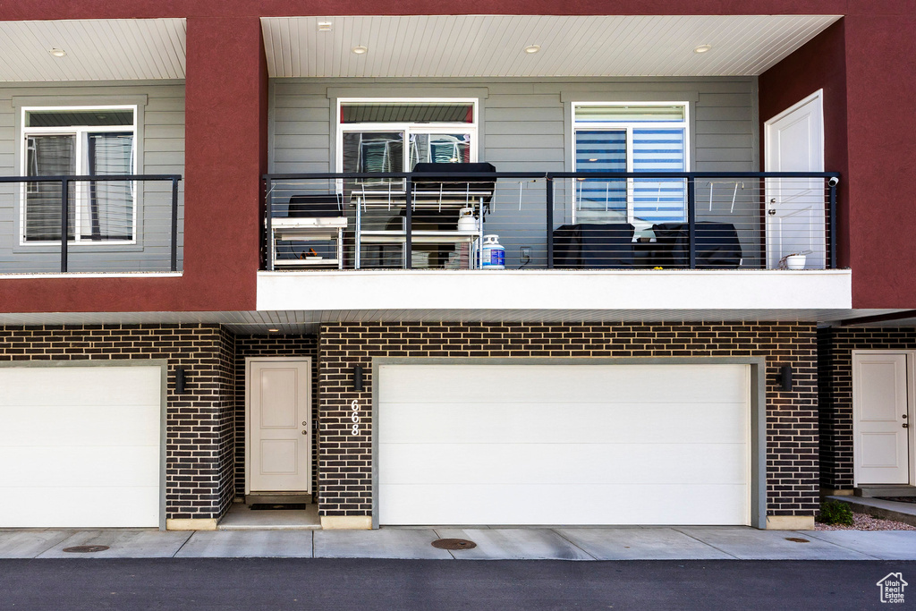 View of front of home with a garage, a balcony, and brick siding