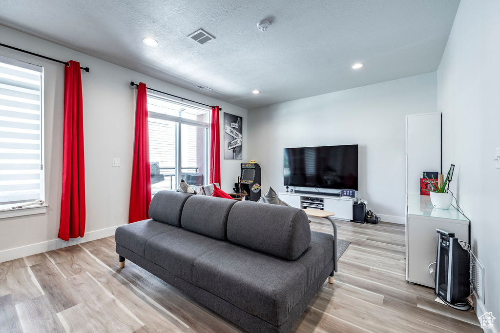 Living room with a textured ceiling and light hardwood / wood-style floors