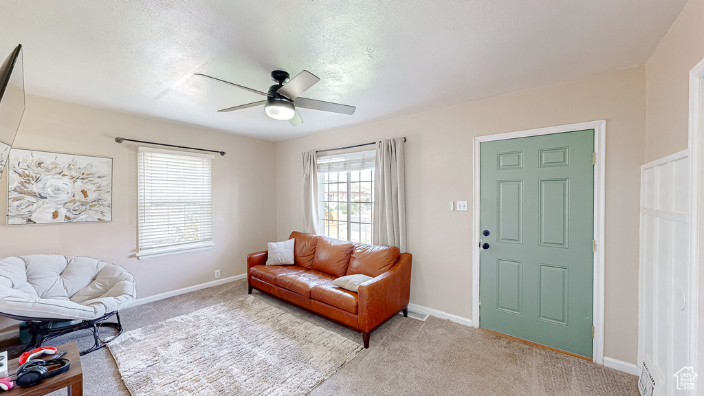 Carpeted living room featuring a textured ceiling and ceiling fan