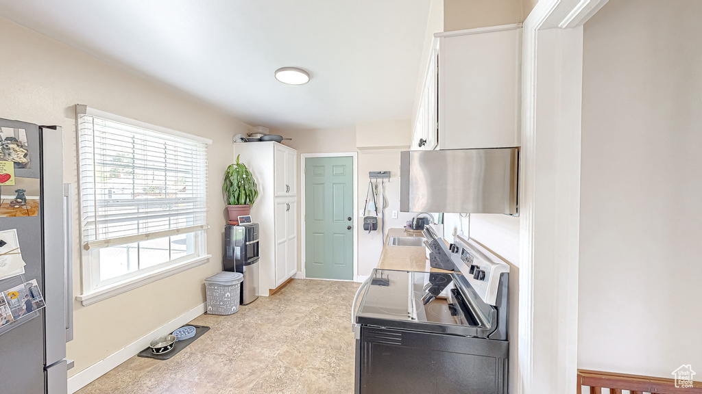 Kitchen featuring electric stove, white cabinetry, and sink