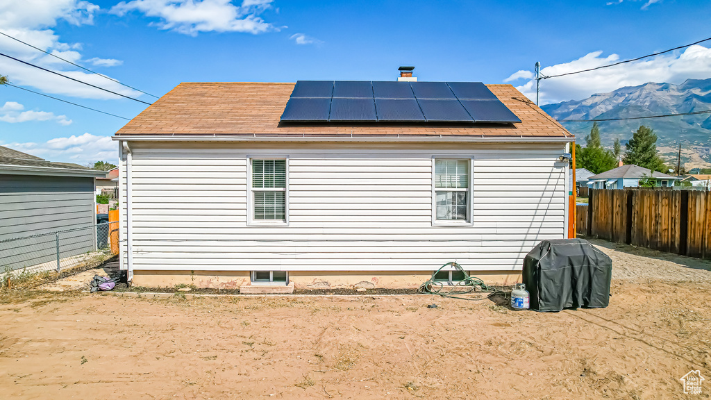 View of property exterior featuring a mountain view and solar panels