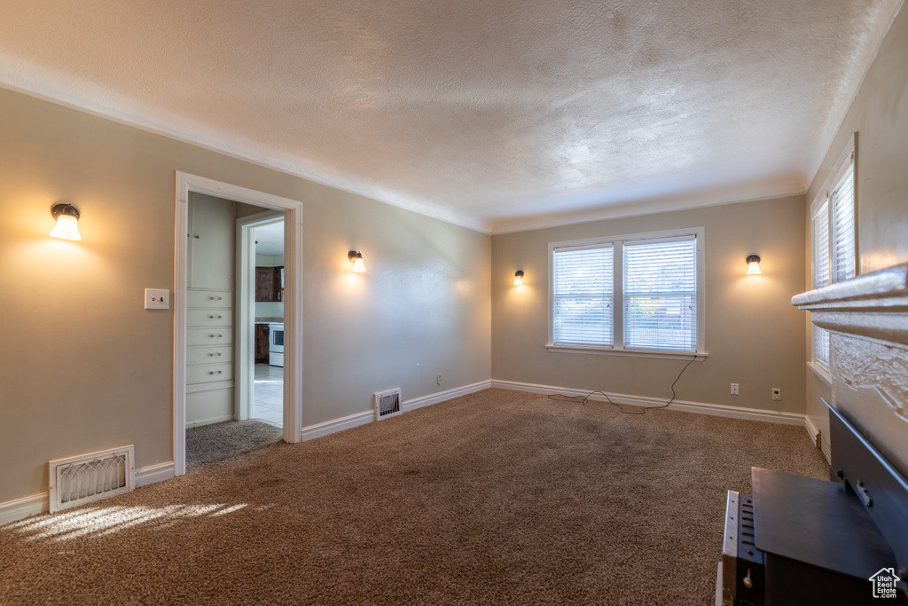 Unfurnished living room with carpet flooring, a textured ceiling, and a high end fireplace