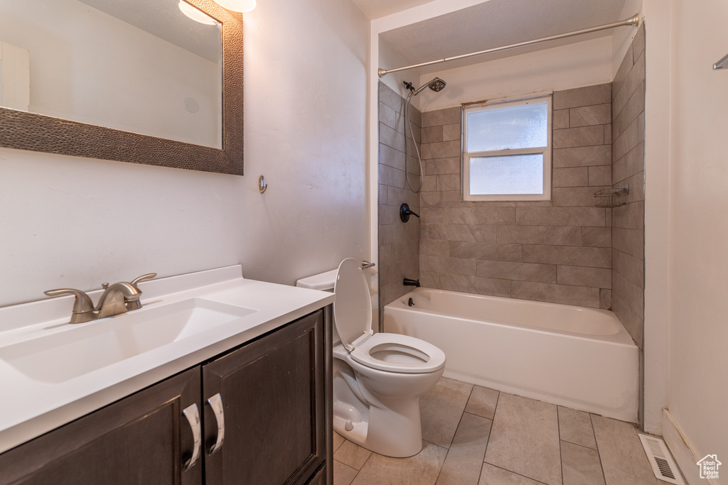 Full bathroom featuring tiled shower / bath combo, tile patterned floors, toilet, and vanity