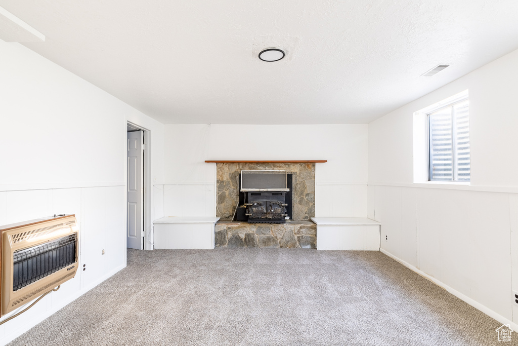 Unfurnished living room featuring carpet floors, heating unit, and a fireplace