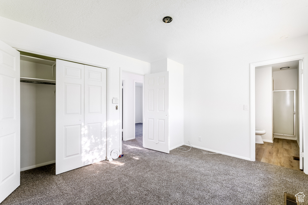 Unfurnished bedroom with carpet floors, a textured ceiling, a closet, and ensuite bath