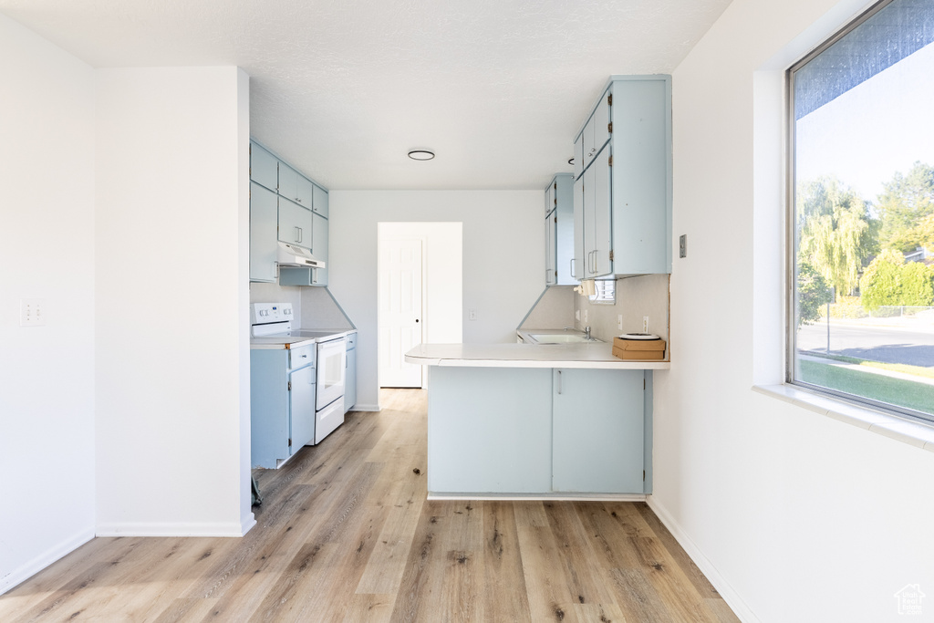 Kitchen featuring light hardwood / wood-style floors, blue cabinets, a breakfast bar, kitchen peninsula, and electric range