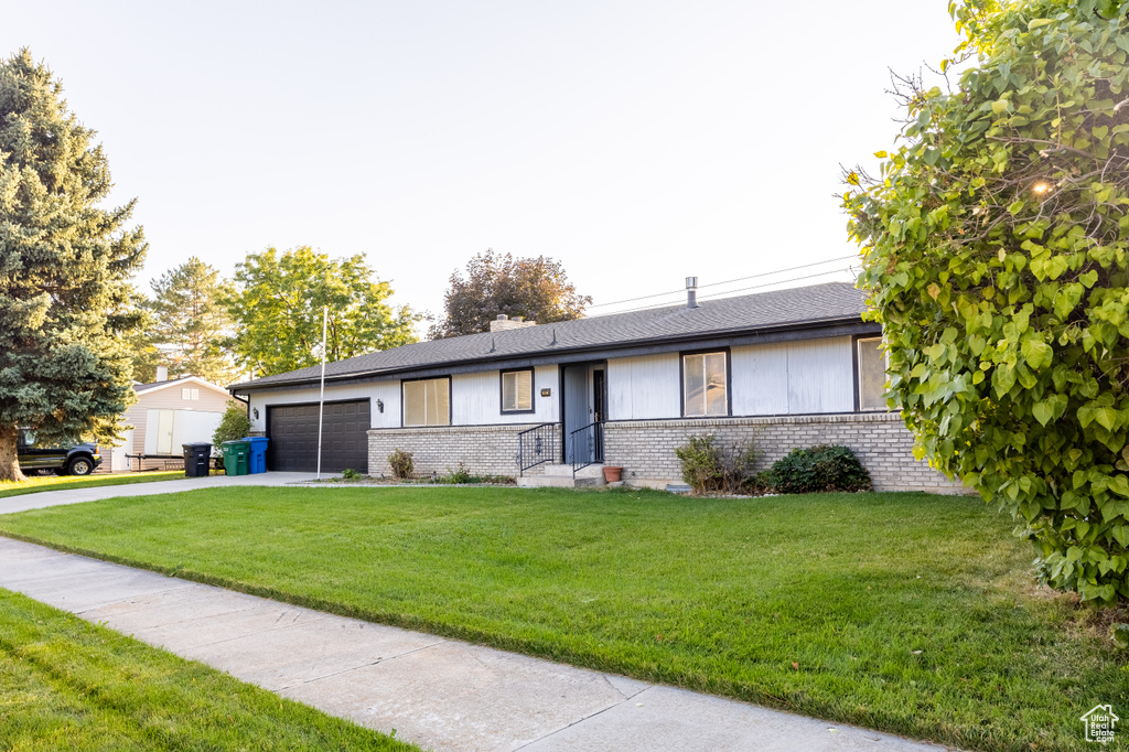 Ranch-style home featuring a front yard and a garage