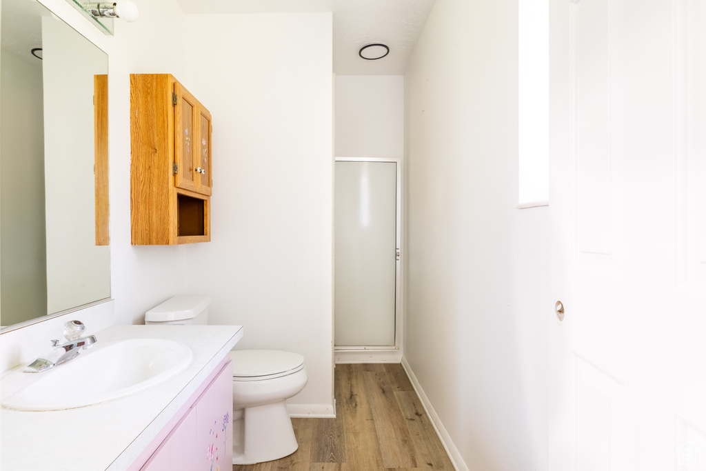 Bathroom with vanity, toilet, an enclosed shower, and hardwood / wood-style flooring