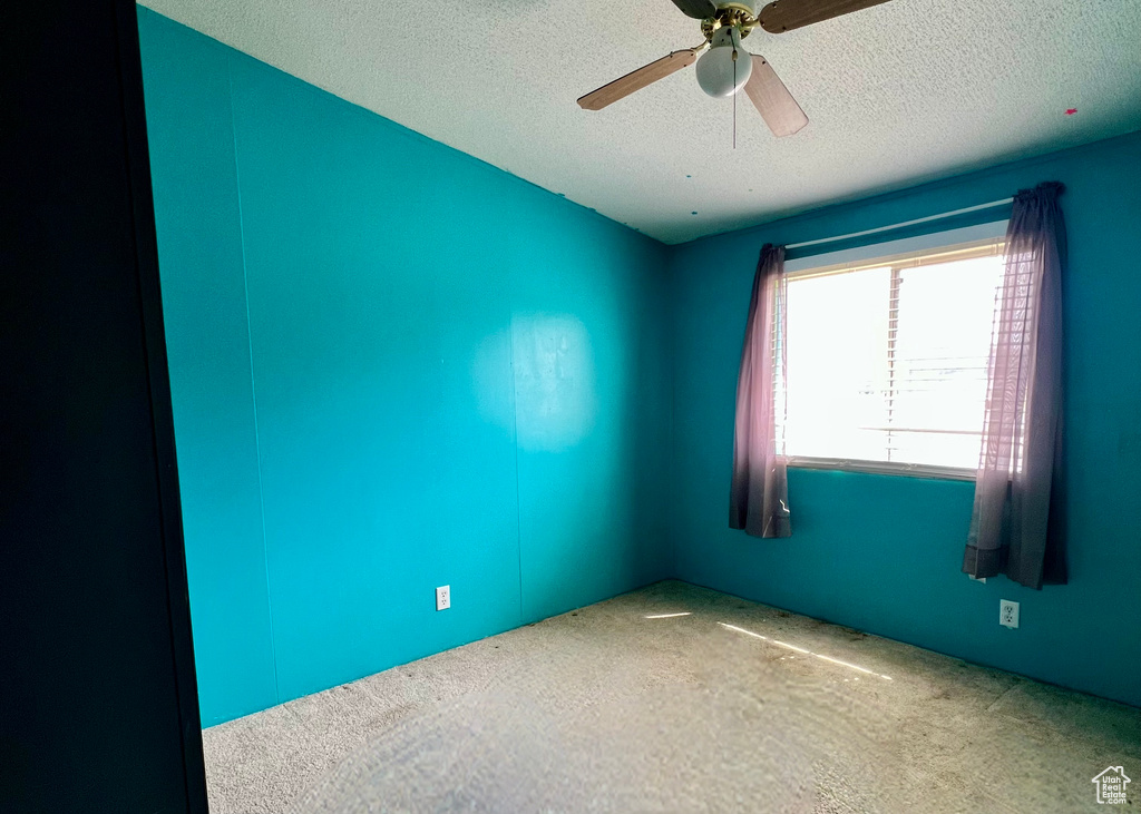 Carpeted spare room with a textured ceiling and ceiling fan
