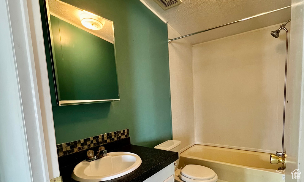 Full bathroom with backsplash, toilet, vanity, shower / bathing tub combination, and a textured ceiling